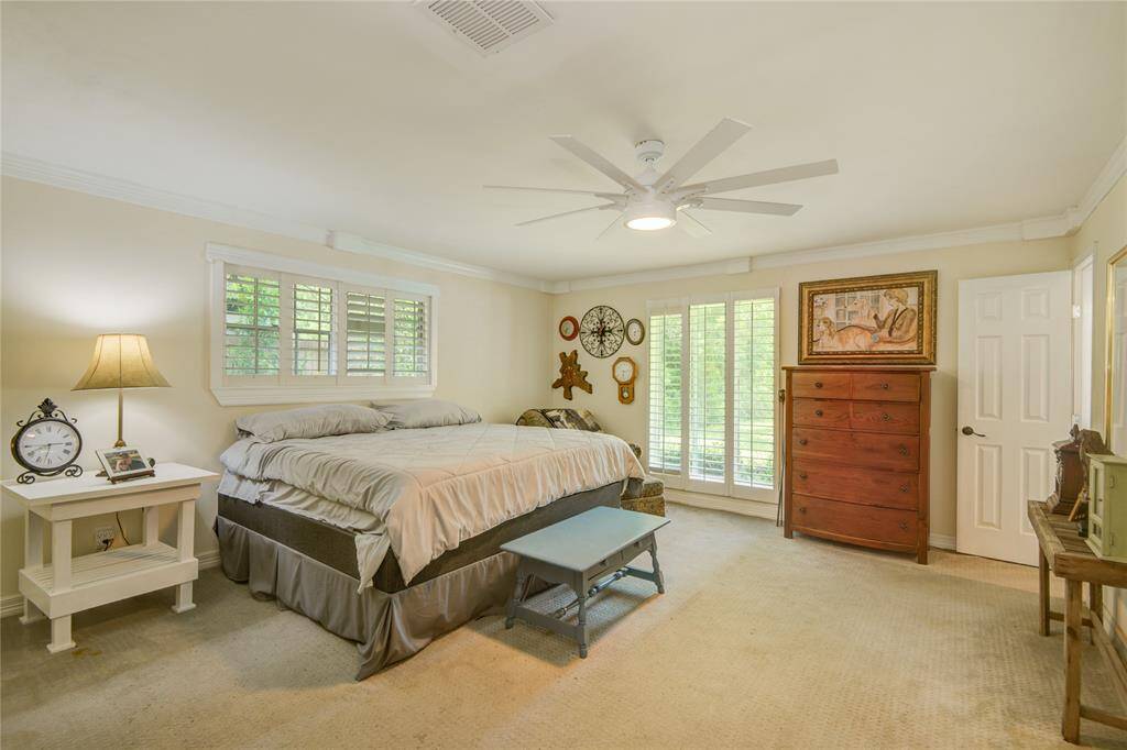 The primary bedroom features floor-to-ceiling windows with serene backyard views, a spacious walk-in closet, and a private ensuite bath with a walk-in shower.