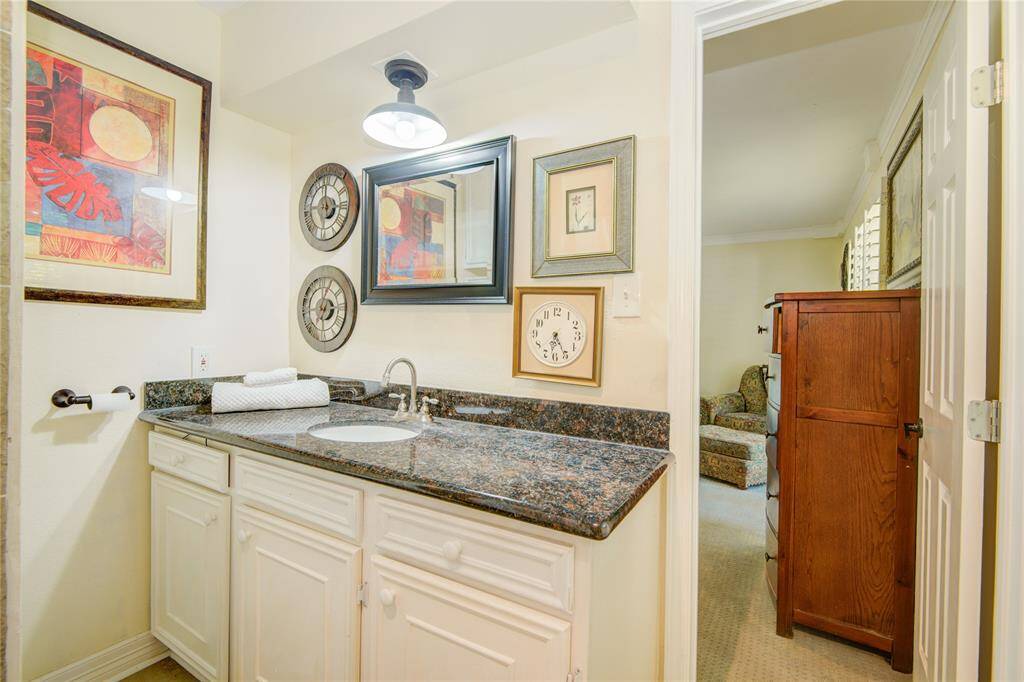 This bathroom view highlights ample cabinet storage and offers a subtle glimpse into the adjoining primary bedroom.