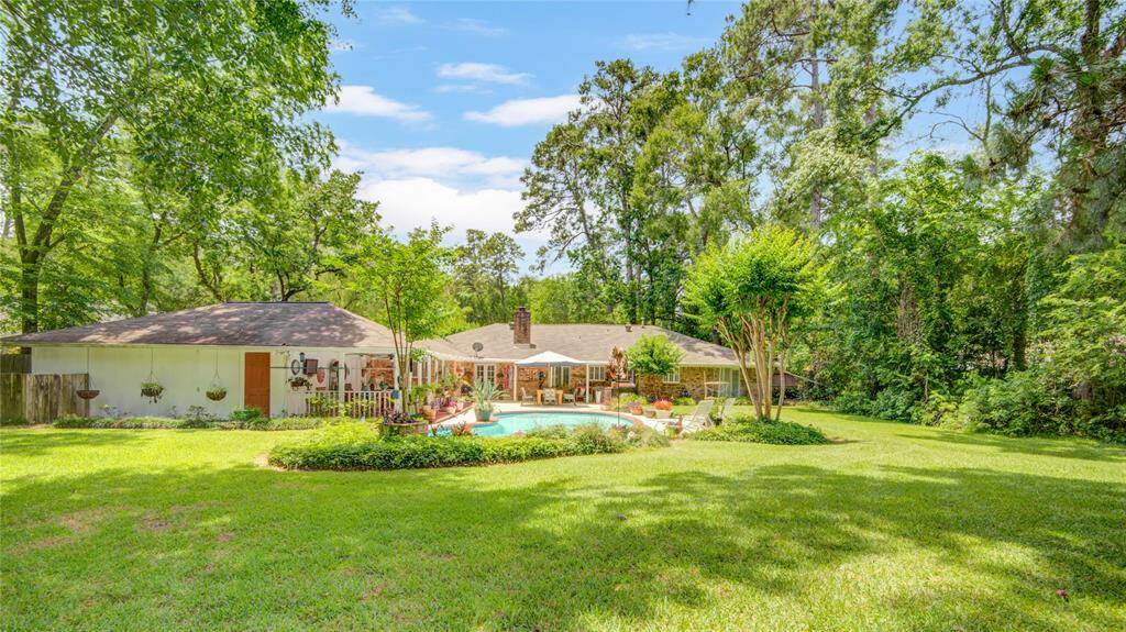 This view from the rear of the yard toward the home beautifully captures the expansive lot size, showcasing generous outdoor space and lush surroundings.