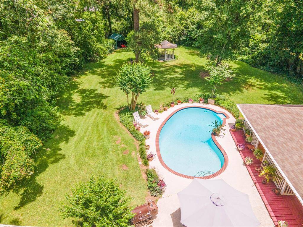 This high aerial view captures the full scale of the property, showcasing the expansive yard, sparkling pool, and beautifully landscaped surroundings that make this home a true private retreat.