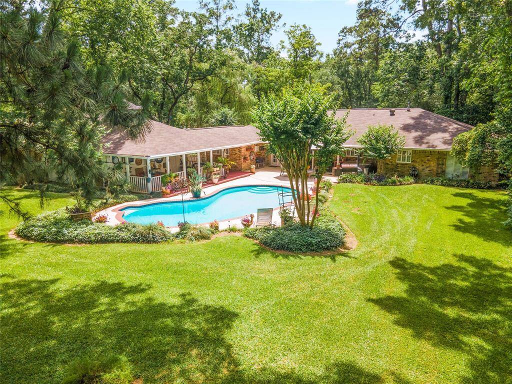 This serene aerial view of the back of the property highlights the peaceful setting, with lush greenery, a sparkling pool, and a sense of seclusion that feels like a private oasis.