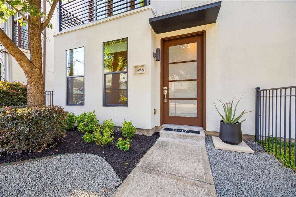 The pathway is elegantly landscaped with expanded shale and greenery. A mature tree adds charm to the front yard.
