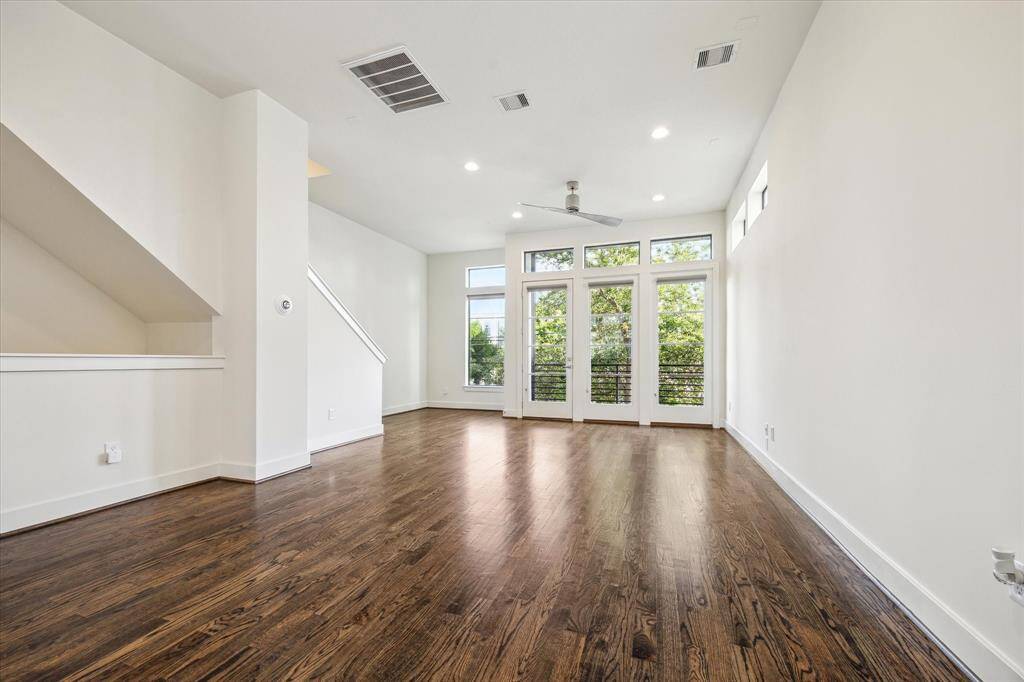 Living room features rich hardwood floors & high ceilings with recessed lighting.