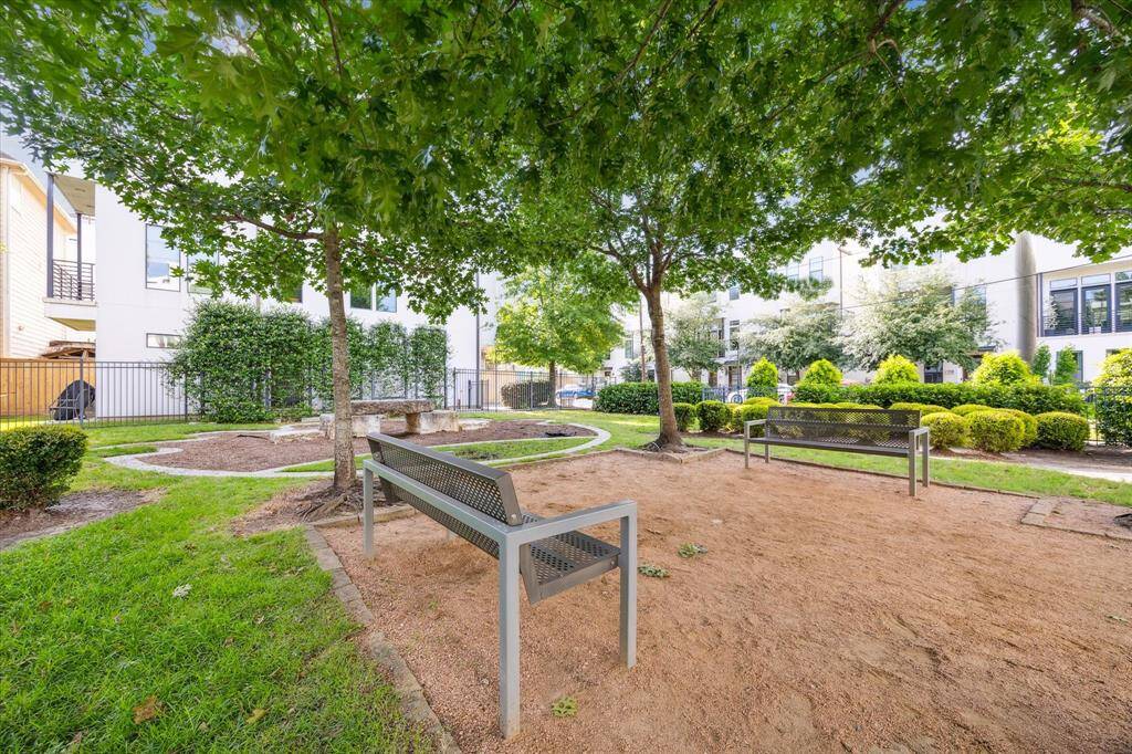 Serene outdoor area with lush greenery, benches, and trees, offering a peaceful space for relaxation or walking the dogs.