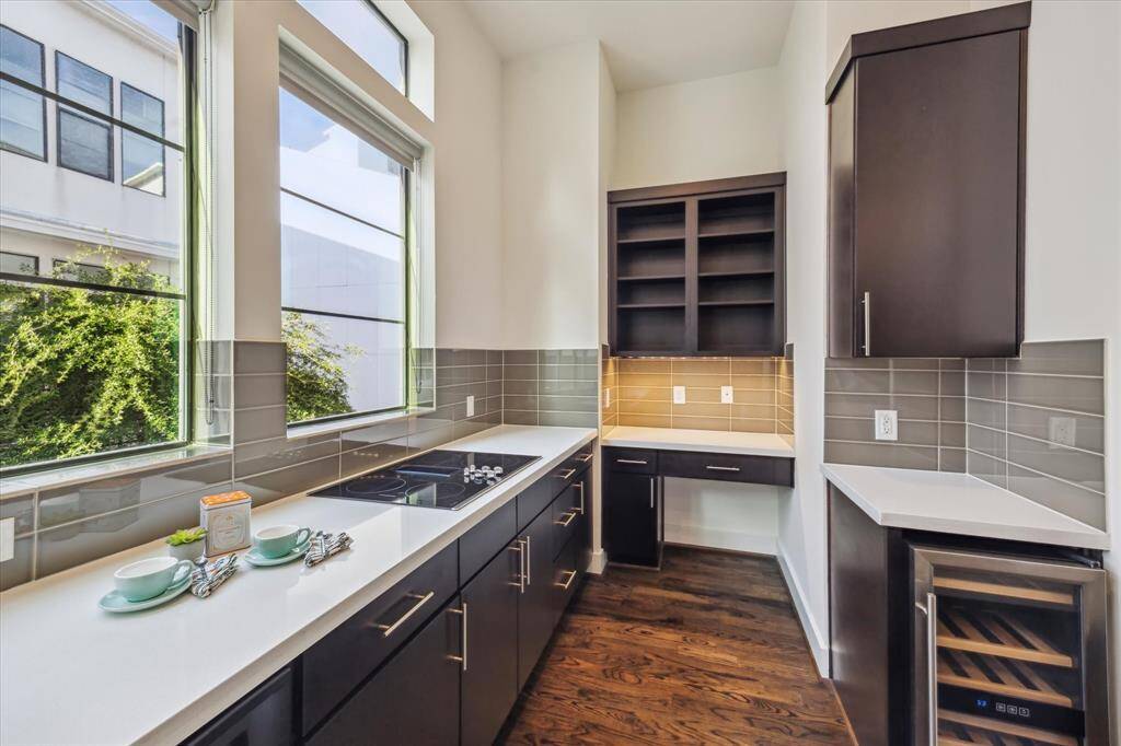 This space features glass tile backsplash, electric cooktop and a wine cooler.
