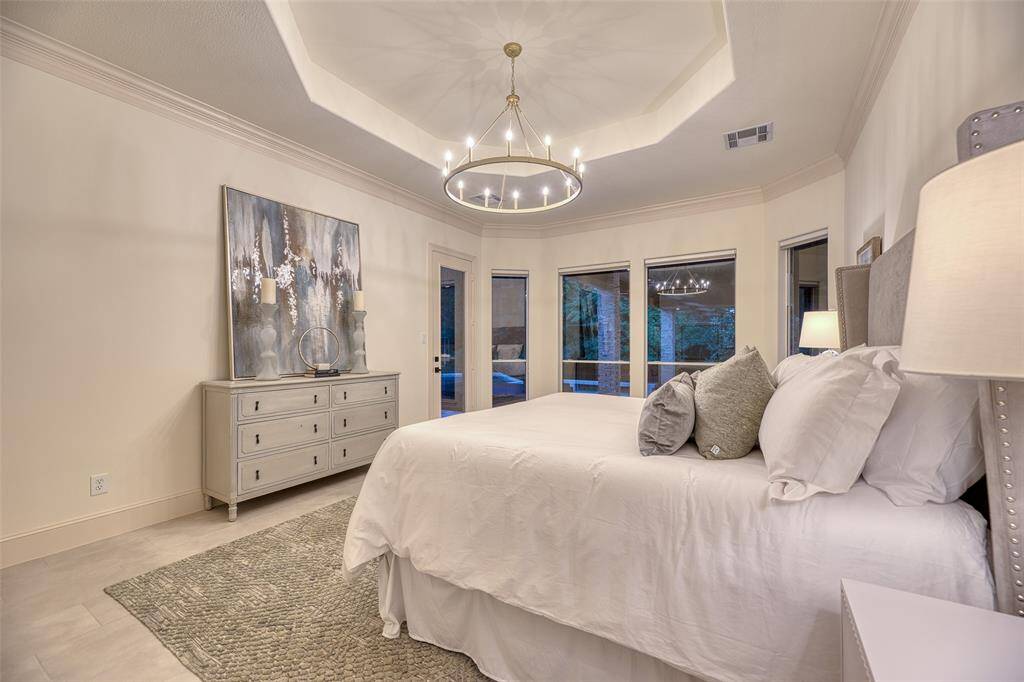 Spacious primary bedroom with tray ceiling, fresh paint, and serene views of the private backyard.