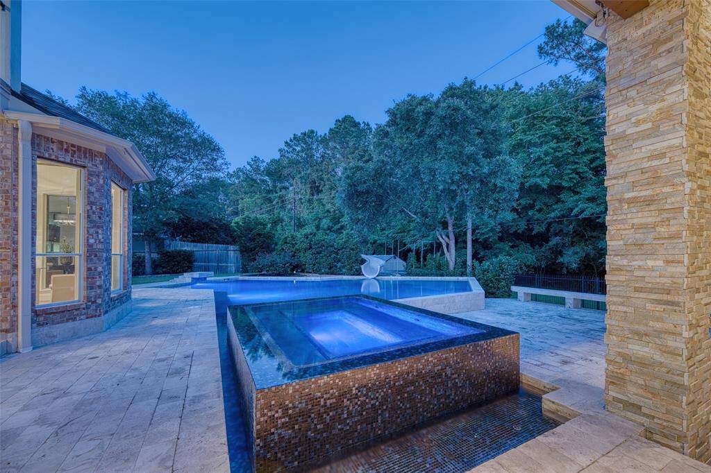 View from the covered patio toward the pool and wooded backdrop creates a peaceful vibe.