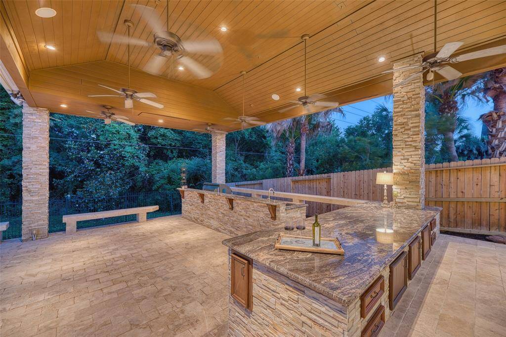 Outdoor kitchen with full oven, cooktop, grill, sink, dishwasher refrigerators and seating potential for the ultimate backyard hosting experience.