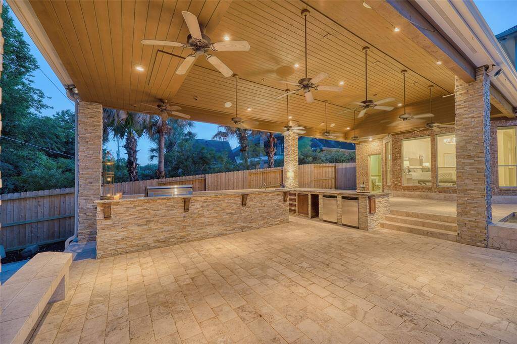Stylish and functional built-in grill setup tucked beneath the patio, overlooking the pool and wooded views.