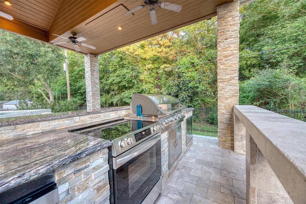 Outdoor kitchen with full oven, cooktop, grill, sink, dishwasher refrigerators and seating potential for the ultimate backyard hosting experience.