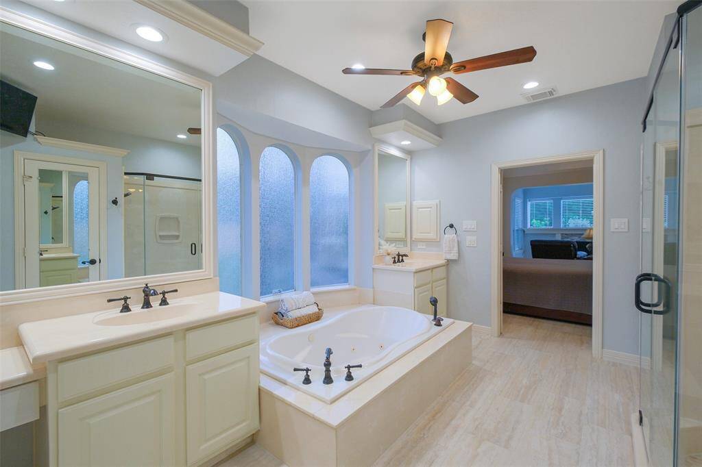 Spa-like primary bath featuring dual vanities  with updated fixtures and a spacious jetted tub.