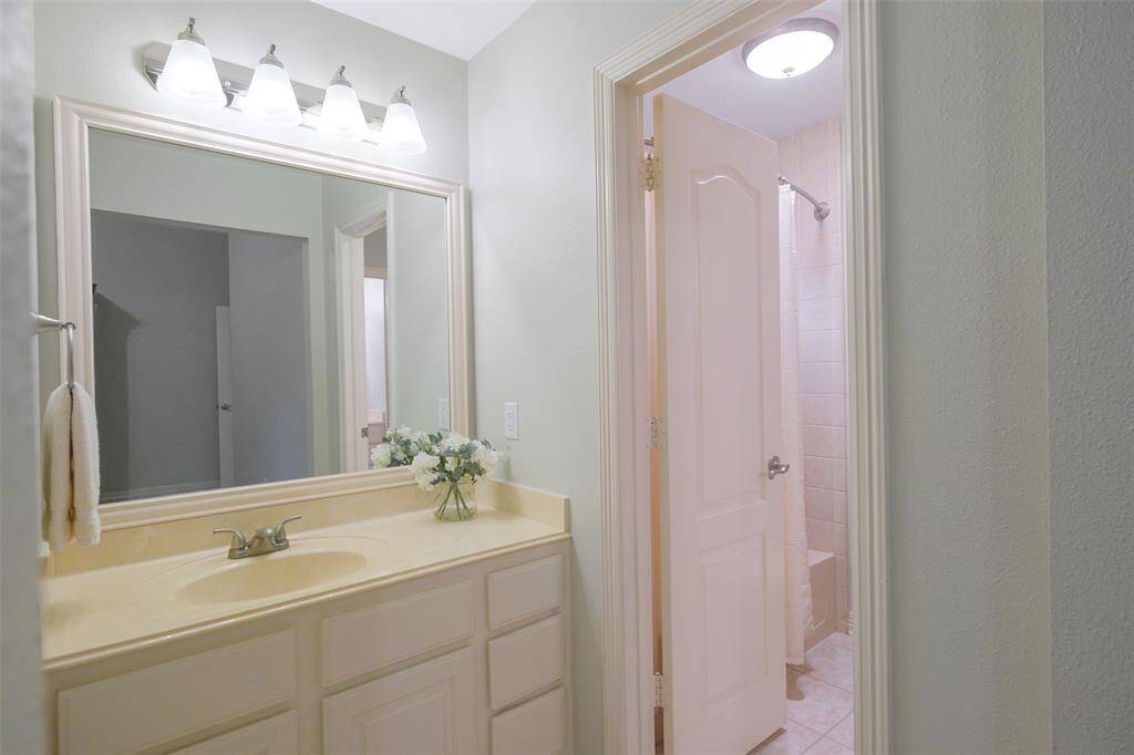Private vanity for bedroom 2 with updated lighting. Shown is shower area that is shared with bedroom 3.