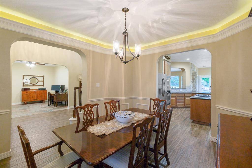 Elegant dining room perfect for large gatherings, featuring crown lighting, a modern fixture, and plantation shutters.