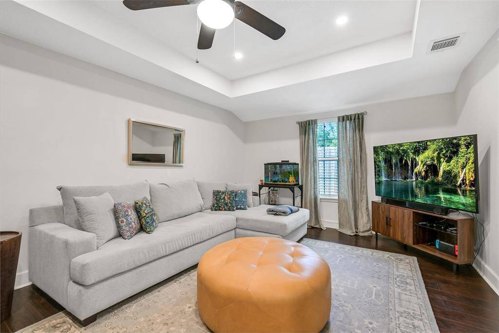 Large family room with tiered ceiling, ceiling fan and storage closet.