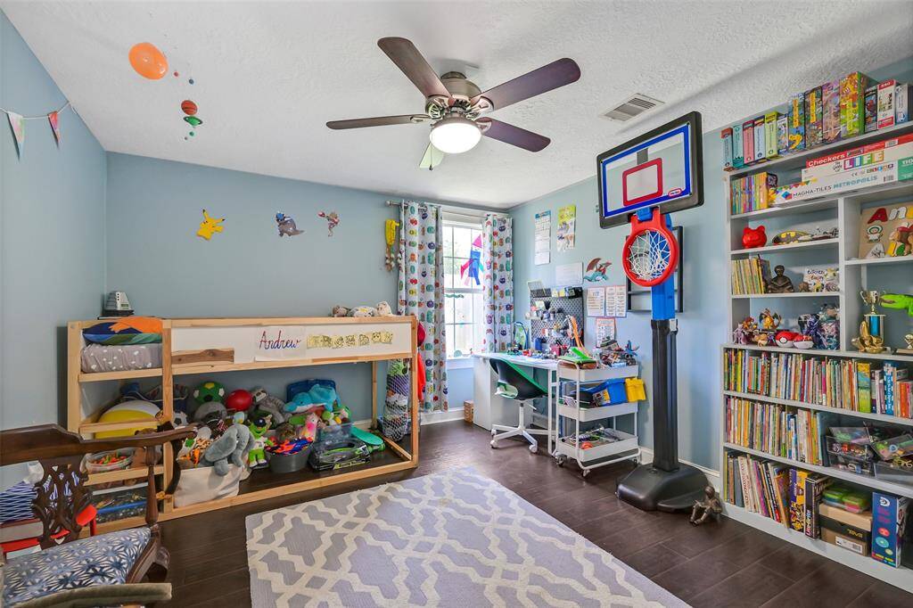 Large secondary room features designer paint, wood floors and ceiling fan.