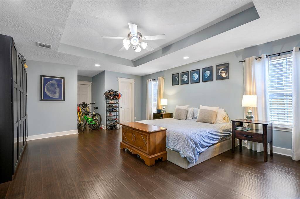 Primary bedroom with private bath, floor to ceiling cabinets, tiered ceiling and 2 inch blinds.