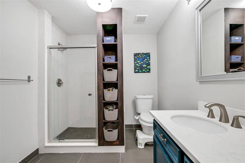 Updated primary bath with quartz counter, designer tile and generous built-ins.