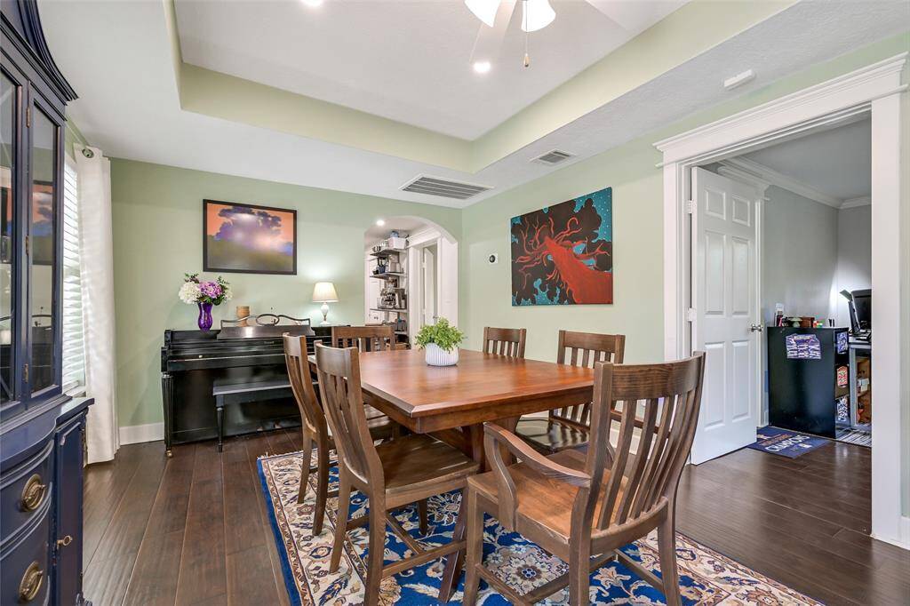 Dining room with designer paint, wood floors and tiered ceiling.