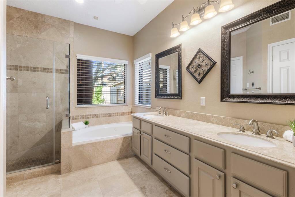 The primary bathroom has a jetted garden tub, dual vanities, and a corner glass shower.