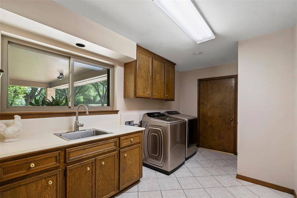 An oversized laundry room with tons of cabinets for storage, a sink for soaking the toughest of stains and a pretty window perched above for those dog days of doing laundry!