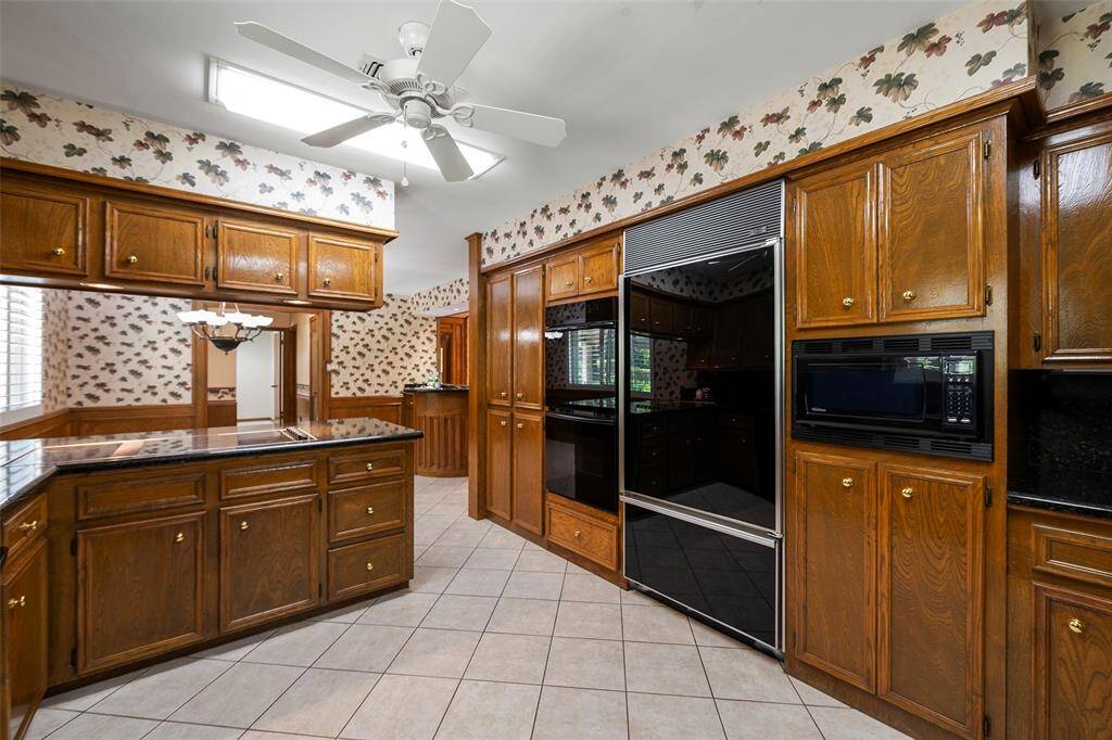 This kitchen features warm-stained cabinets with knobs, custom built-in dual ovens, a built-in refrigerator, microwave and much more!