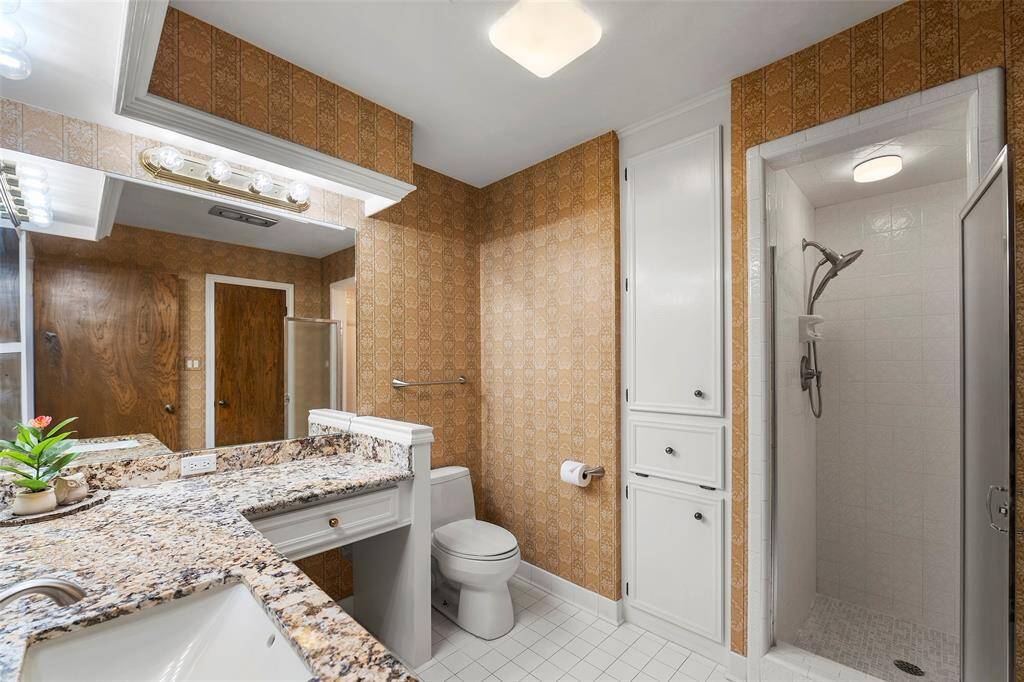 This en-suite bath has gorgeous granite countertops that adorn crisp white cabinets, along with a glass enclosed shower, and linen closets with laundry storage!