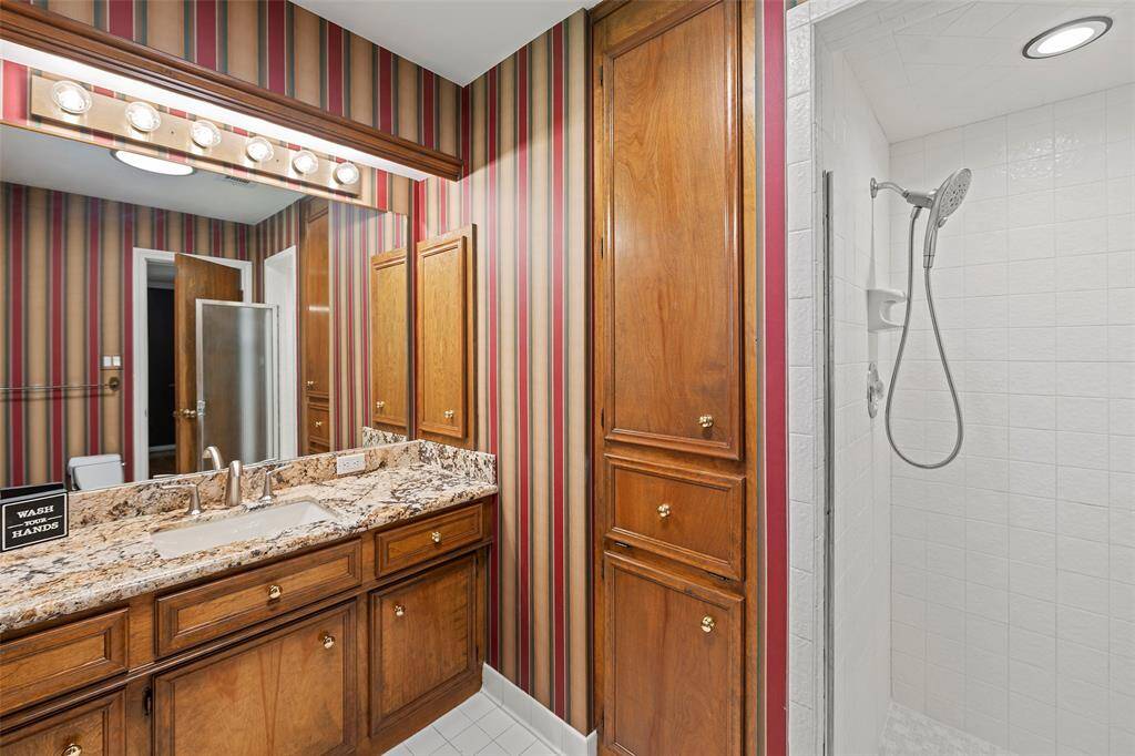 Another full-sized bathroom with glass enclosed shower, granite atop of the warm stained cabinets and a linen closet with laundry storage!