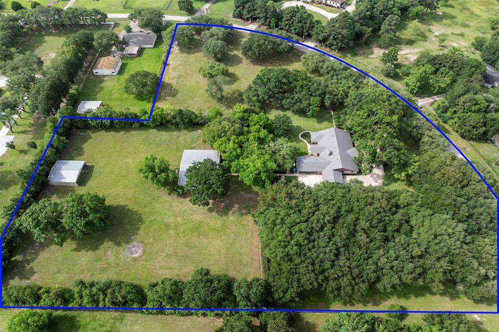 Aerial view of this stunning almost 6-acre estate in the heart of Cypress. Property is cross-fenced and features wide open green space, mature oak trees and exceptional privacy. Includes a beautifully maintained main residence, two large outbuildings and plenty of room for horses.