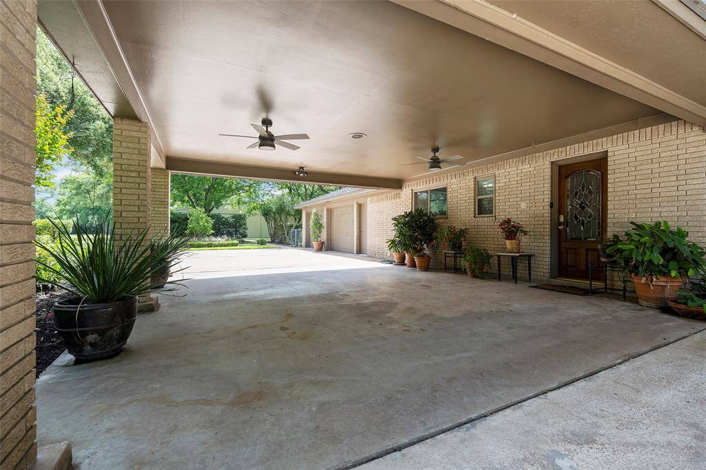 Wonderfully lined with potted plants, and breezy ceiling fans, this porte-cochere provides an additional seating space to sit, relax and enjoy your oasis!  It is also handy for those rainy-day grocery hauls!