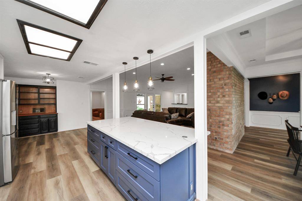 Pendant lighting and elegant columns beautifully frame the kitchen space, while the blue island adds a refreshing pop of color and personality.