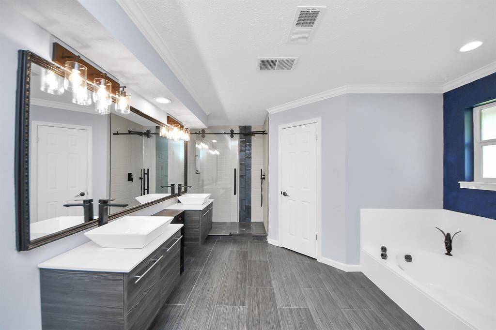 The walk-in shower features newly added rolling barn-style glass doors, while the garden tub provides a relaxing spot to soak and unwind.