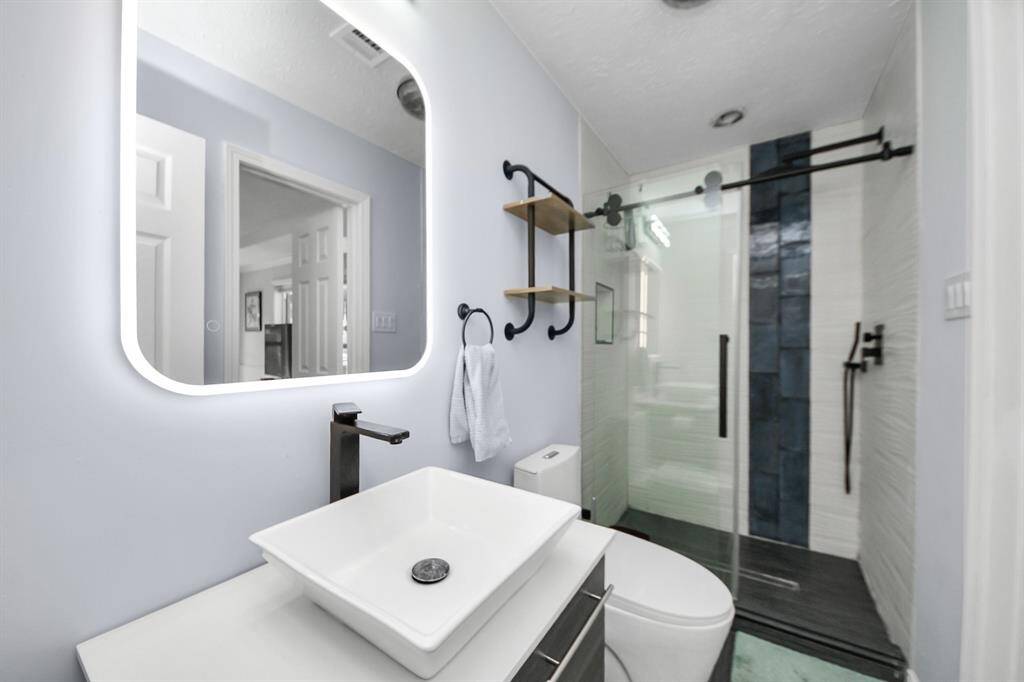 This ensuite bathroom features a modern yet functional design, complete with a walk-in shower and above-counter sink for both style and convenience.