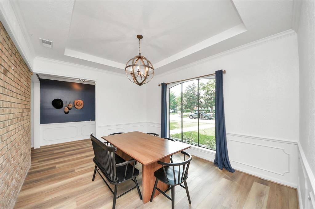 Just off the entry, a generous dining room offers an accent ceiling, a lovely view of the front yard, and a striking brick wall backdrop—blending character and charm for effortless entertaining.