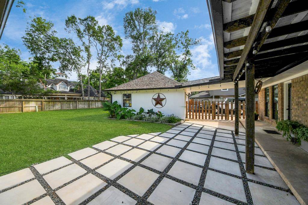 Just beyond the covered patio, a modern paver walkway separated by crushed granite adds a sleek, contemporary touch and leads into the expansive backyard.
