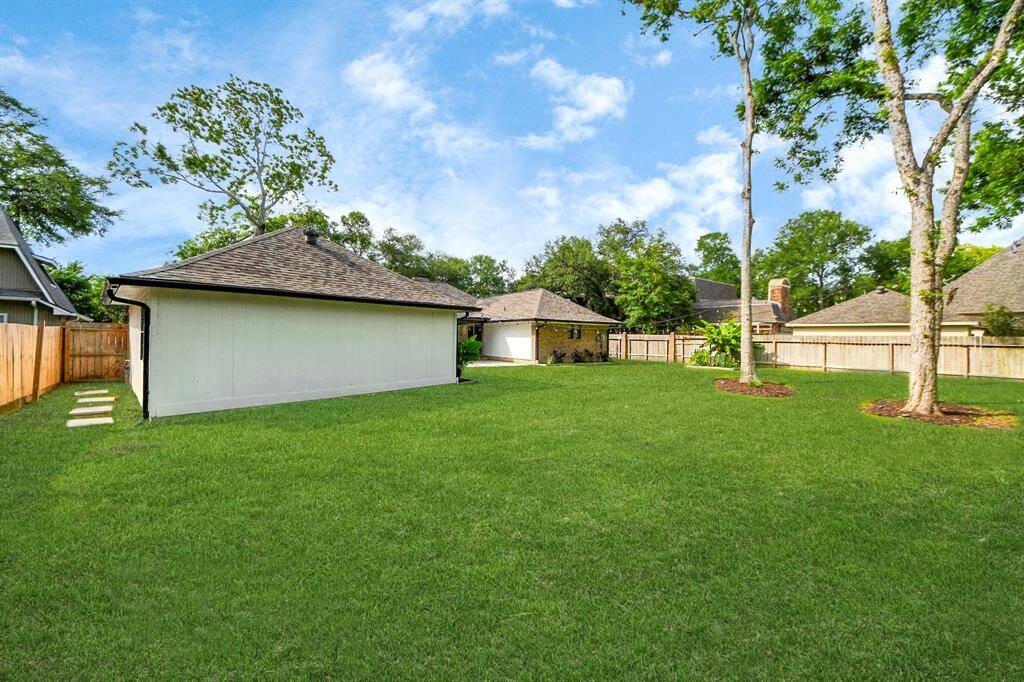 An oversized detached garage provides ample space for cars and storage. Between the garage and fence, a paver-lined walkway over grass offers easy access.