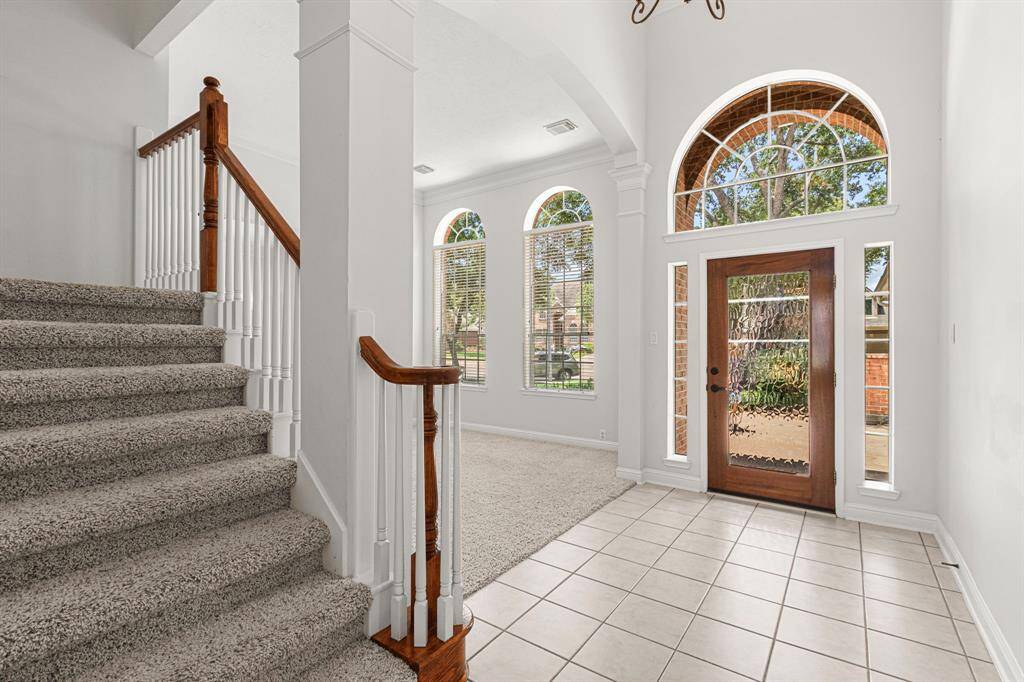 Front door has arched window above it, matched by double arched windows in formal living room.