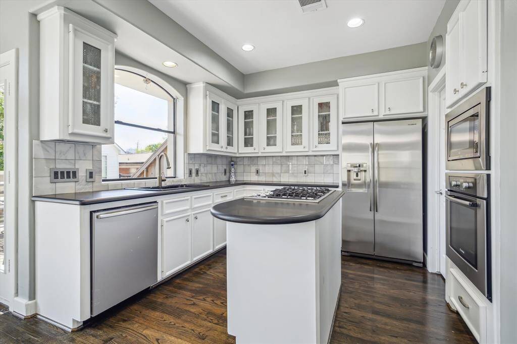 Kitchen island has gas cooktop and there is ample counter and cabinet storage. Window above the sink allows for natural light, microwave, convention single oven and an walk-in pantry.