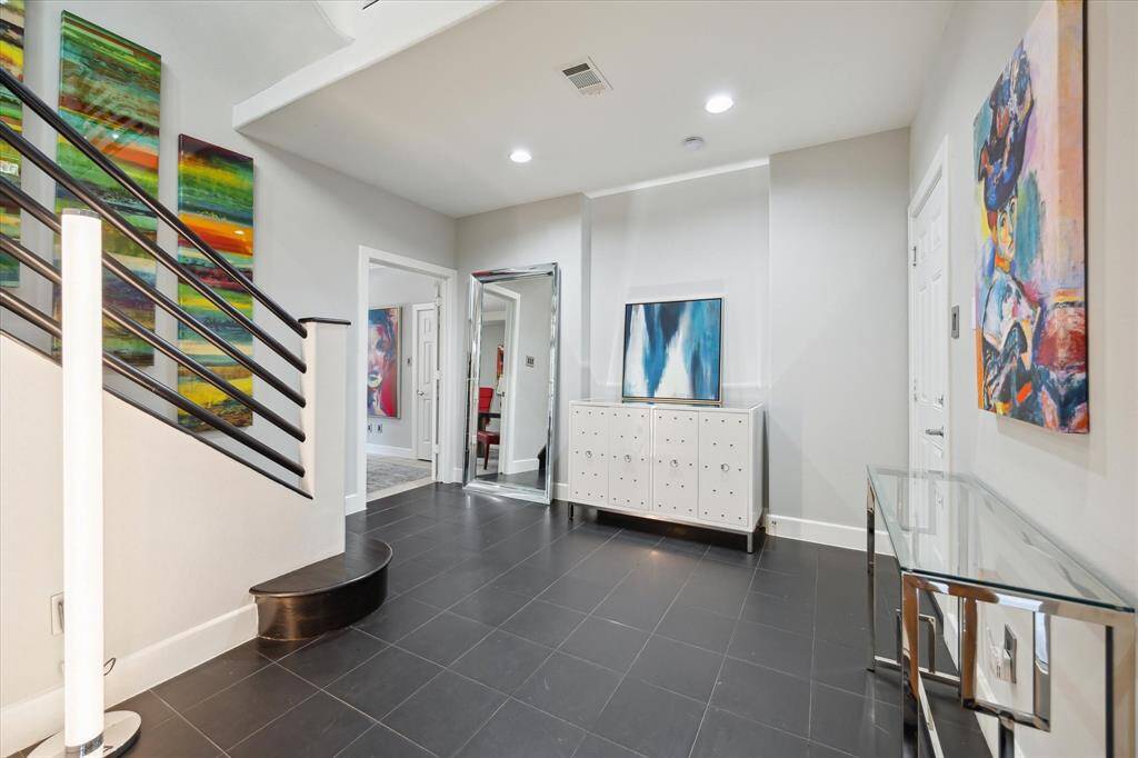 Front glass door opens onto this spacious foyer, with open ceiling, tile flooring, access to first floor bedroom and garage.