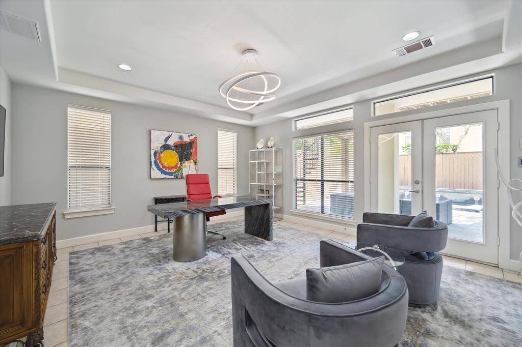 First floor guest bedroom or flex room Warm soothing wall color, high ceilings, tile flooring, French doors lead to outdoor covered patio and pool area.