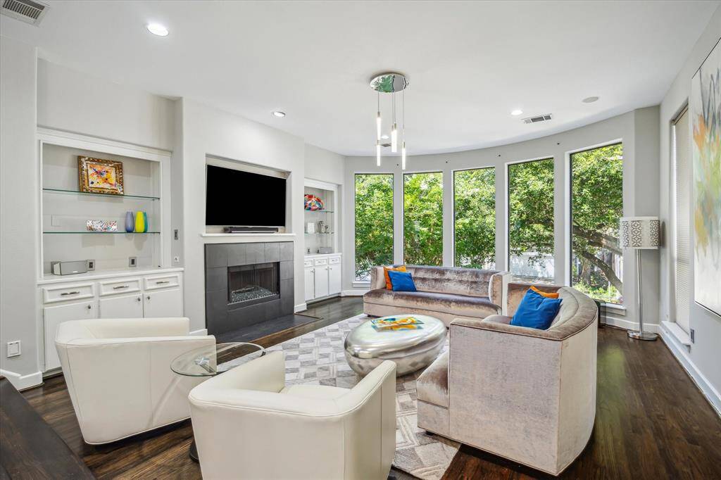 Second floor living room, high ceilings, built-in shelving and storage, gas fireplace and windows allow for natural light. Dark wood floors add to the modern feel of the room.