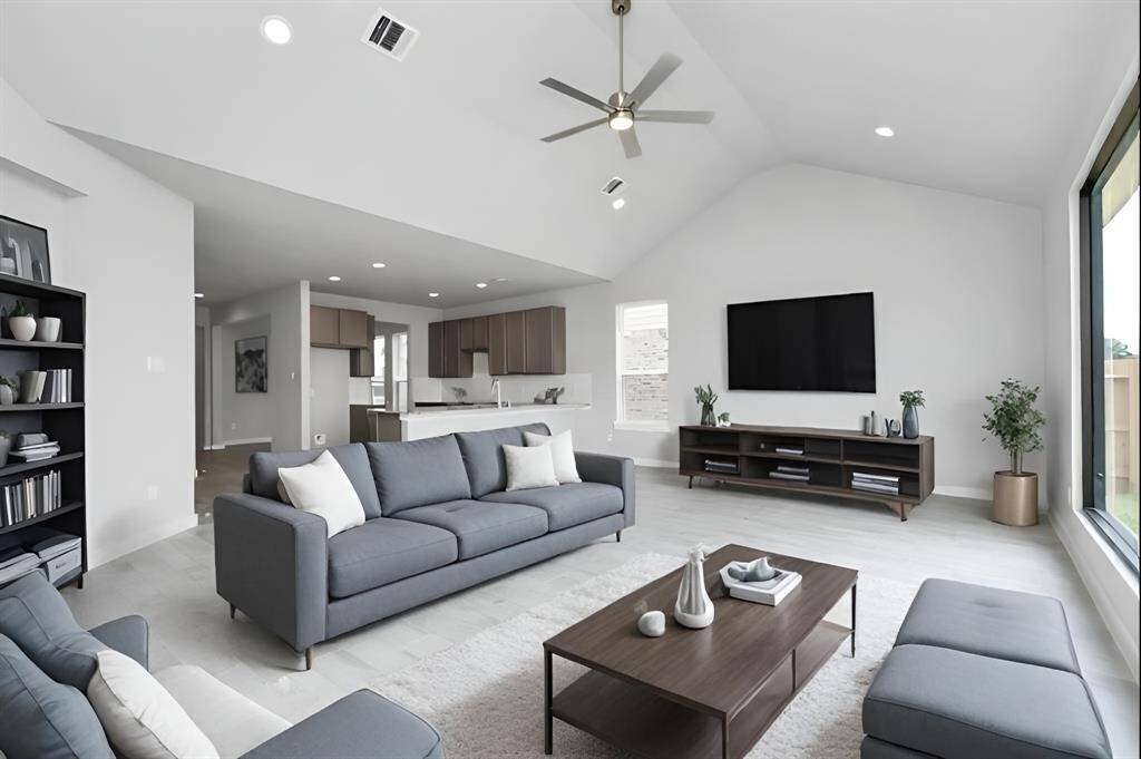 Relax and unwind in this inviting family room, illuminated by abundant natural light streaming in through tall windows, complemented by high ceilings and stunning flooring. Stay comfortable year-round with the gentle breeze from the ceiling fan, creating the perfect atmosphere for family gatherings. Sample photo of completed home with similar floor plan. As-built interior colors and selections may vary.