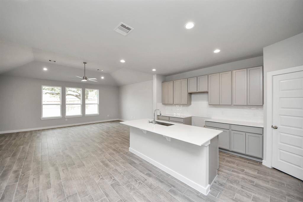 This kitchen is by far any chef’s dream! This spacious kitchen features high ceilings, lightstained wood cabinets, granite countertop, SS appliances, modern tile backsplash,recessed lighting, extended counter space, granite kitchen island with double sink, andspace for breakfast bar, and a walk-in pantry all overlooking your huge family room.
