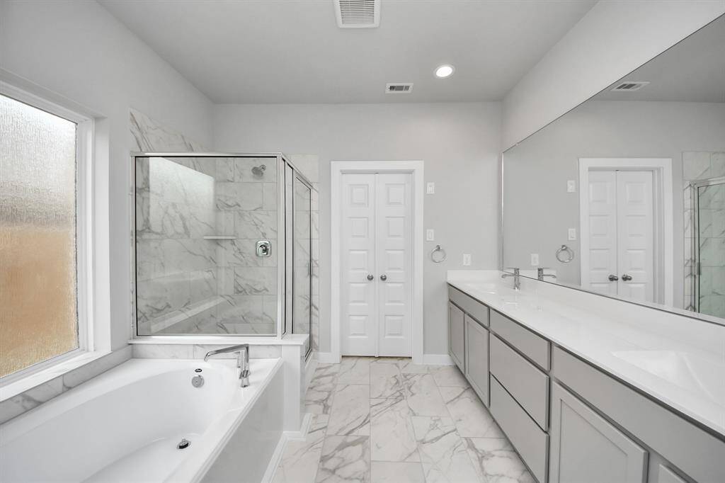 Indulge in a spa-like retreat within the confines of this primary bathroom.Delight in a spacious walk-in shower enveloped in stylish tile surround and unwindin a separate garden tub adorned with custom detailing.
