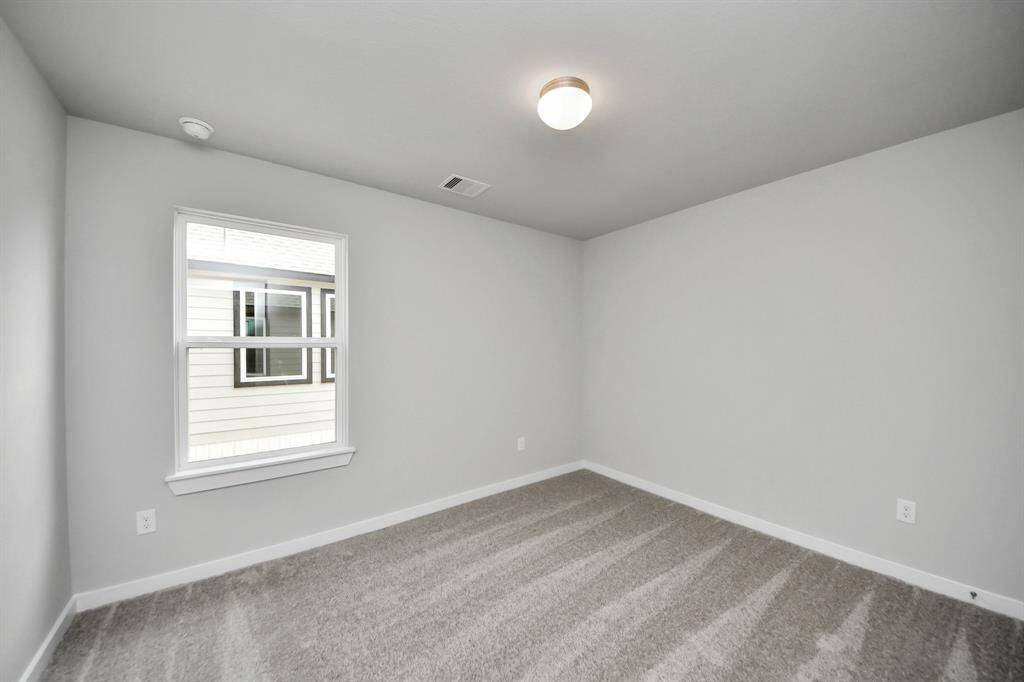 Secondary bedroom features plush carpeting, large windows that let in plenty of naturallight, bright paint, and spacious closets.