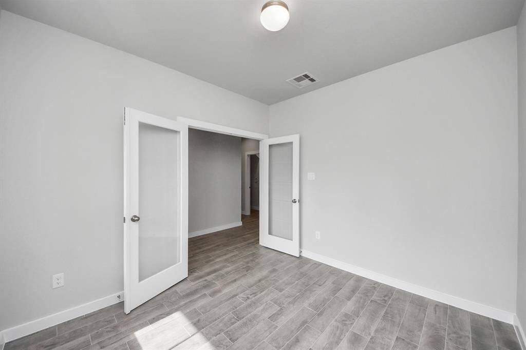 Experience the perfect blend of sophistication and warmth in this home office,boasting elegant wood-look tile flooring and flooded with natural light fromexpansive windows and French doors.
