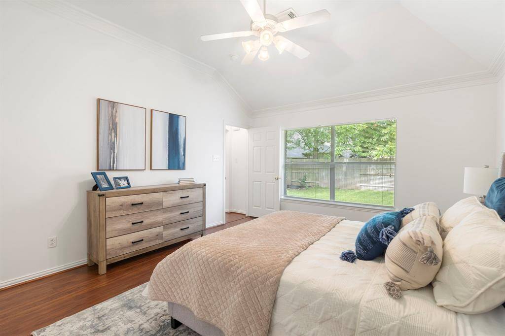 This bedroom features a modern design with a neutral color palette. It has a large window providing ample natural light and a view of the backyard.  The room opens to an en-suite bathroom, adding convenience and luxury.