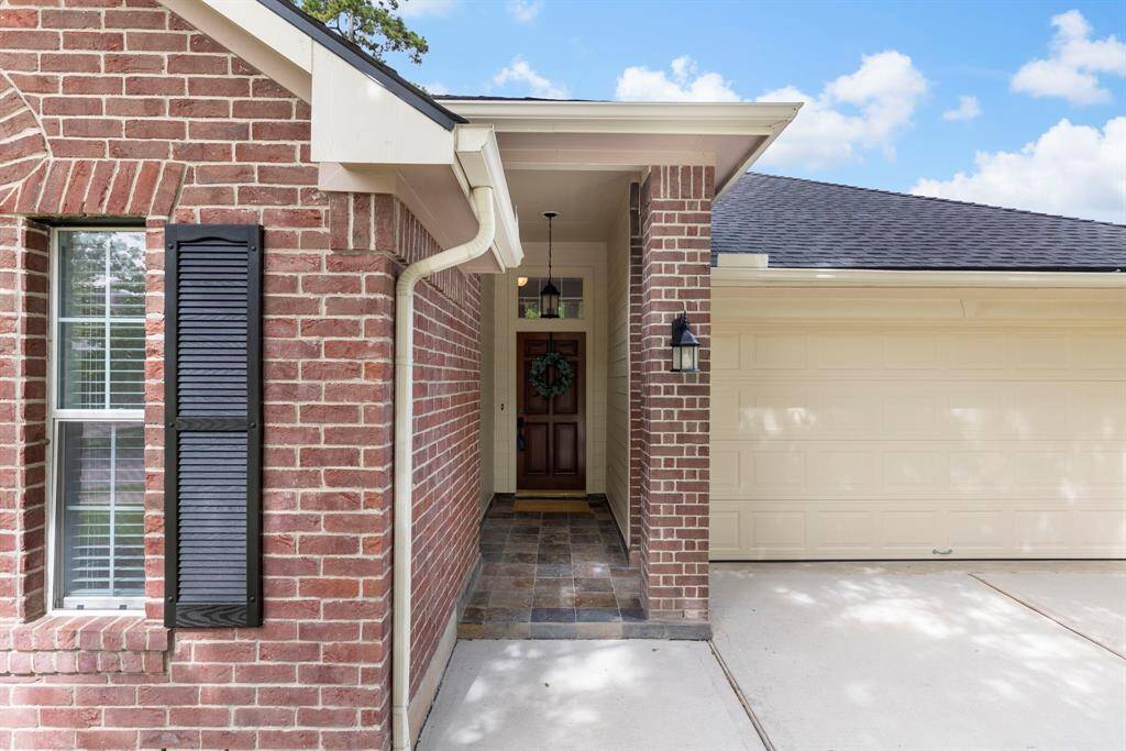 A welcoming front entrance features a covered porch and elegant lighting. The attached garage provides convenience, and the window with shutters adds character to the home.