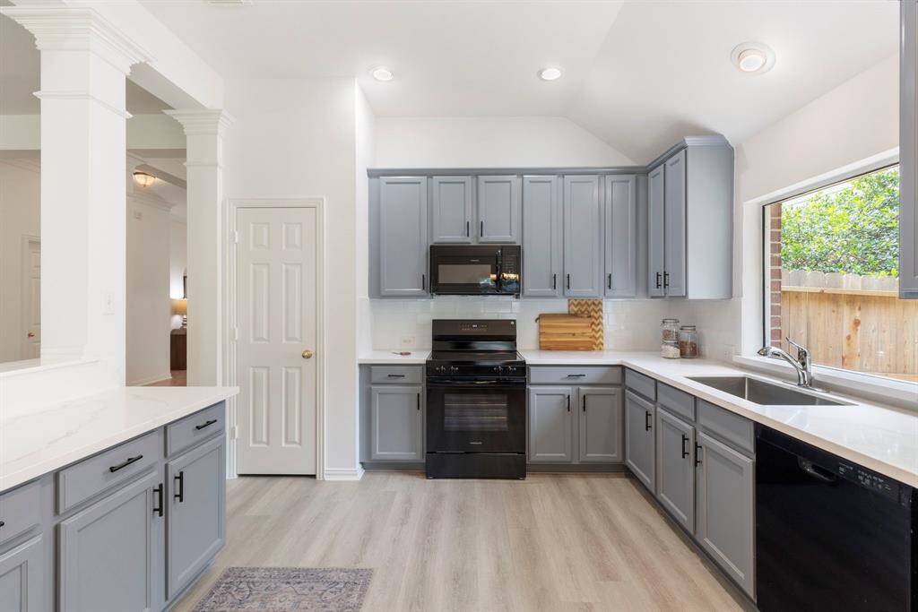 This kitchen features open layout with ample counter space. Large windows offer natural light, and the light flooring adds warmth to the space.