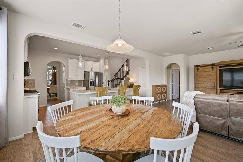 Enjoy your morning coffee or a casual family meal in this eat-in breakfast room that's bathed in natural lights streaming in from windows that encircle the space. Also note the continued luxury vinyl plank floors, pendant lighting, and half-glass panel back door.
