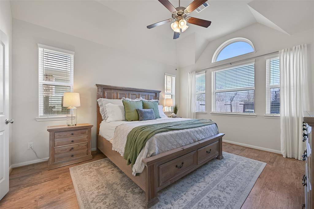 The owner's retreat is secluded on the first floor, just off of the side of the family room. Here, you'll note an 11-foot high gambrel ceiling with a lighted ceiling fan, luxury vinyl plank floors, and a trio of palladium arched windows overlooking the backyard.